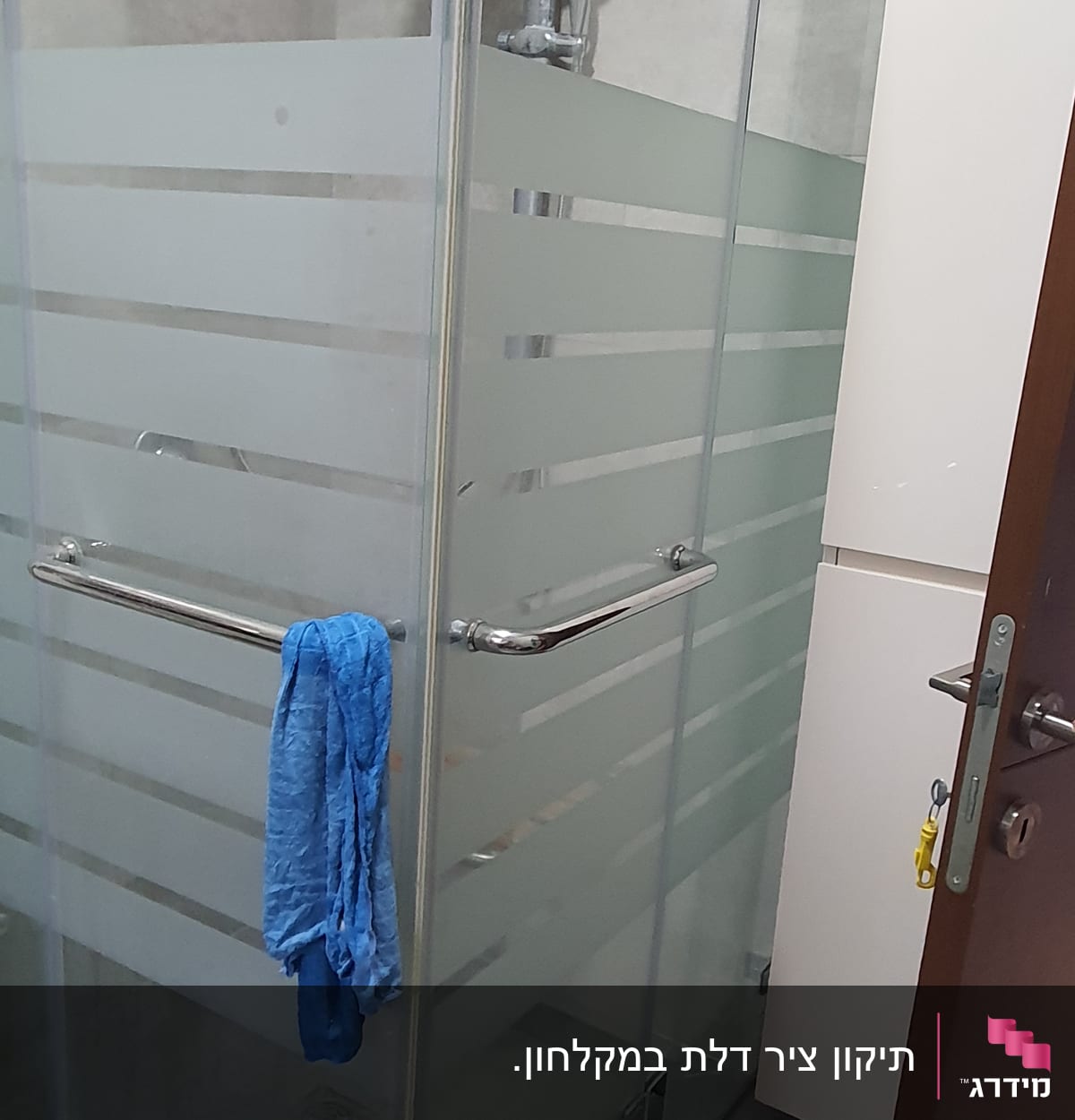 מקלחון זכוכית עם מגבת כחולה תלויה